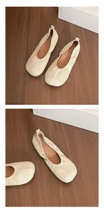 Detailed view of elegant cream soft leather faux split-toe ballet flats on a wooden floor