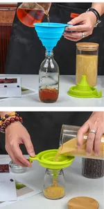 Detailed view of the foldable silicone funnel pouring grains and liquids into glass bottles.