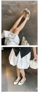 Detailansicht eleganter cremefarbener Ballerinas mit schwarzen Schleifen und Rundspitze