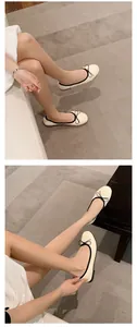 Lifestyle-Detailansicht cremefarbener Ballerinas mit schwarzem Rand und Schleife.