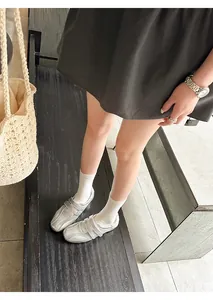 Dettaglio di sneaker stile ballerina argento metallizzato con cinturini in velcro sul modello.