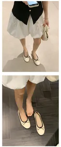 Detailansicht von cremefarbenen Ballerinas mit schwarzer Schleife an den Füßen des Models