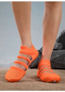 Close-up of orange water shoes with breathable mesh upper on a sandy beach