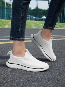 Vista lateral de zapatillas de caminar blancas de malla para mujer en pista exterior