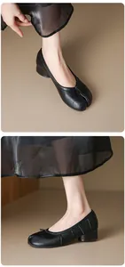 Close-up detail of black leather split-toe Tabi shoes with pleated texture and block heel