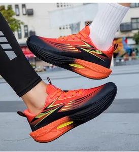 Close-up of vibrant orange and black running shoes with lightning accents on a sidewalk.