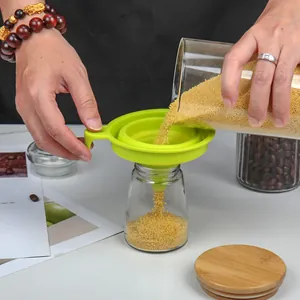 Multi-purpose collapsible green silicone kitchen funnel used for pouring dry grains into glass jar