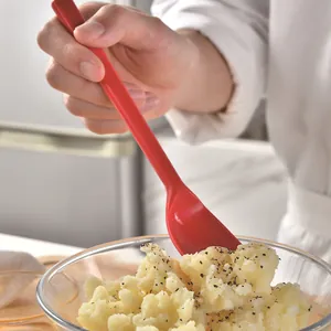 Cucchiaio in silicone rosso alimentare per pappe neonato in una ciotola di vetro