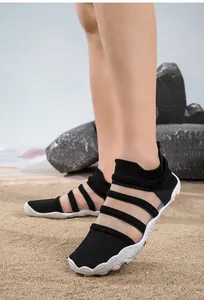 Detailed side view of black breathable mesh water shoes with white anti-slip soles on beach sand