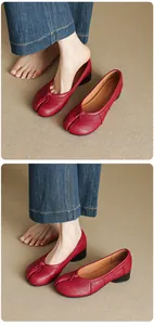 Detailed macro view of red leather Tabi split-toe pumps with mid-block heel and knot detail.