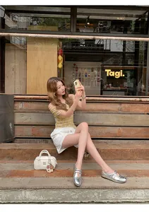 Asiatisches Modell trägt silberne Mary-Jane-Schuhe mit Klettverschluss in Lifestyle-Umgebung