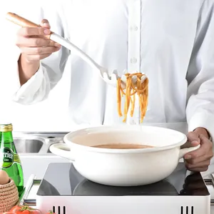 Cuchara de silicona blanca para pasta con mango de madera levantando fideos de la olla