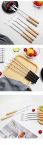 Detailed set of stainless steel fruit forks with natural wood and black handles