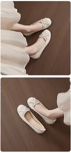 Detail shot of beige French-style ballet flats with delicate bow on wooden floor