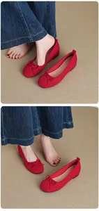 Close-up detail of red French-style ballet flats with bows shown on feet with denim