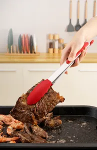 Heat resistant silicone tipped stainless steel food tongs lifting a juicy grilled steak