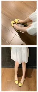 Detailaufnahme gelber Ballerinas mit schwarzer Schleife auf einem hellen Holzboden
