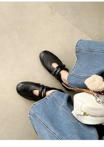 Detailaufnahme von schwarzen Mary Jane Schuhen mit Klettverschluss und blauer Jeans