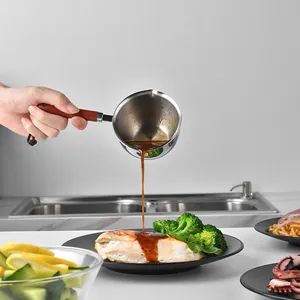 304 stainless steel small melting pot with wooden handle pouring sauce onto food in kitchen