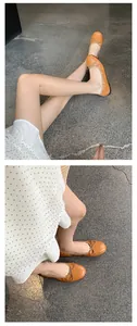Detailaufnahme stylischer orangefarbener Ballerinas mit Schleife und runder Kappe