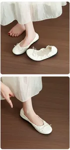 Close-up of white French ballet flats with delicate bow tie and soft elastic sole