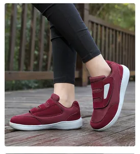 Detail view of burgundy senior walking shoes with double velcro straps on a wooden deck