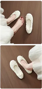 Detailed view of white French bow ballet flats with soft soles on a wooden floor.