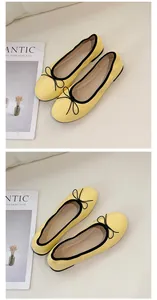 Detailansicht gelber Ballerinas mit schwarzer Paspelierung und eleganter Schleife