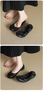 Close-up of model wearing black French-style ballet flats with delicate bow tie