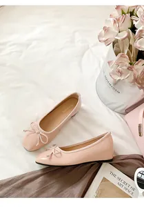 Detailed shot of elegant pink patent ballet flats with a delicate bow on white bedding