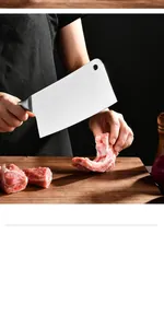 Macro detail of a professional stainless steel meat cleaver cutting meat on a wooden board.
