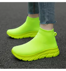 Vue détaillée des baskets chaussettes montantes vert néon en maille sur sol asphalte.