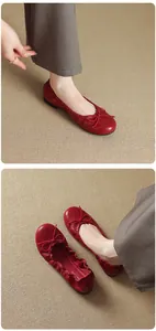 Close-up detail of red French ballet flats with bow, worn on a woven mat background