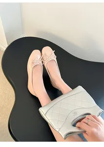 Close-up view of pink patent leather ballet flats with bow detail on a black table.