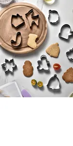 Top-down view of various Christmas-themed stainless steel cookie cutters on a marble surface
