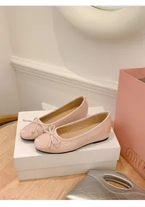 Elegant detail view of pink patent leather ballet flats with bow accents on a white box