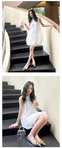 Elegant silver pointed-toe flats featuring a decorative gold buckle shown on black stairs
