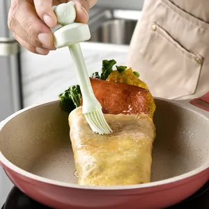 Light green silicone oil brush with cute pig head handle used for basting food in a frying pan