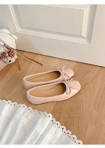 Detailed view of elegant pink French style ballet flats with bow decor on wooden floor