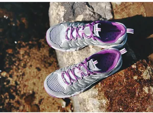 Top view of breathable grey mesh hiking shoes with purple laces on rocky terrain