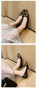 Close-up of black pointed-toe flats featuring a hammered gold metal buckle on a model's feet.