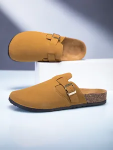 Vue latérale de sabots en daim marron avec semelle en liège et boucle en métal