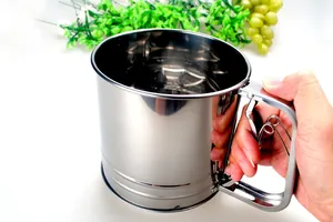 Handheld macro view of a large stainless steel double-layer flour sifter cup