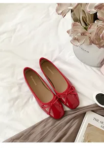 Detailed view of red French ballet flats with bow accents on white textured linen