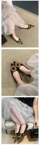 Elegant detail of black pointed-toe flat shoes with a hammered gold metal buckle