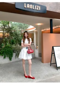 Red French-style ballet flats with bow detail worn in a chic outdoor setting