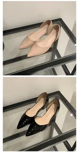Detail view of French style pointed-toe flat shoes in nude and black patent leather