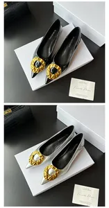 Detailed view of elegant black and silver pointed-toe flat shoes with irregular gold buckles