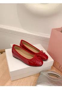 Elegant red patent leather ballet flats with bow detail on a white display box