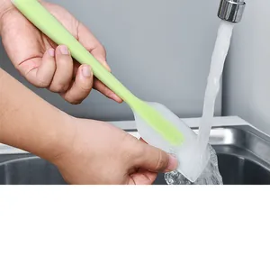 Close-up showing the easy-to-clean feature of a green silicone spatula under running water